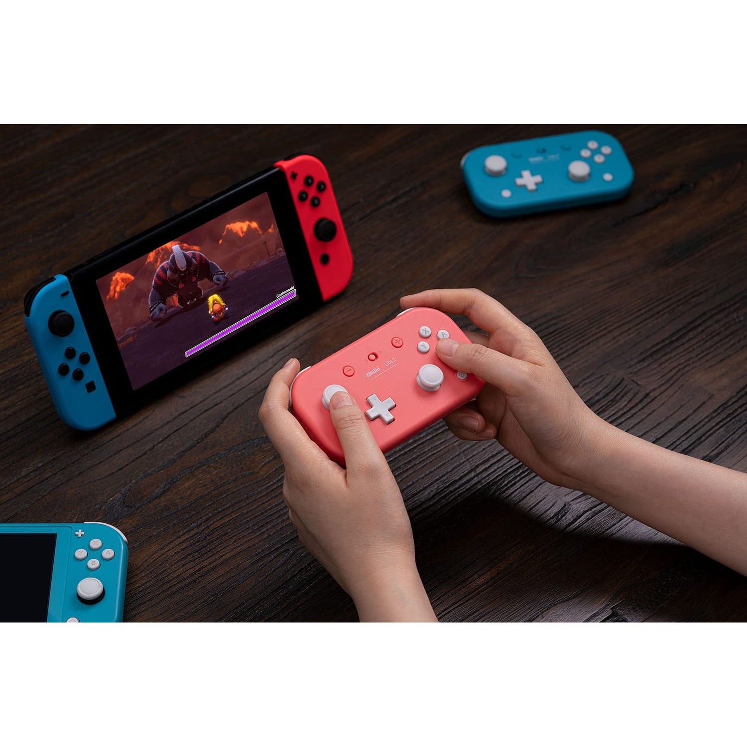 Hands using 8BitDo Lite 2 Bluetooth controller in pink while playing on a Nintendo Switch console.