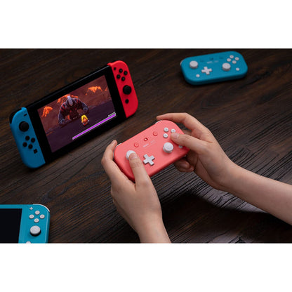 Hands using 8BitDo Lite 2 Bluetooth controller in pink while playing on a Nintendo Switch console.