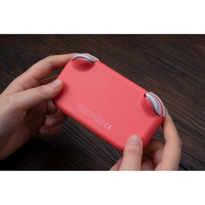 Back view of 8BitDo Lite 2 pink controller being held, showing rear design and product markings.