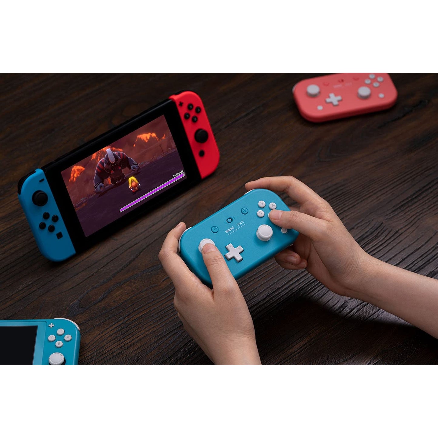 Hands using 8BitDo Lite 2 Bluetooth controller with Nintendo Switch console on a table.